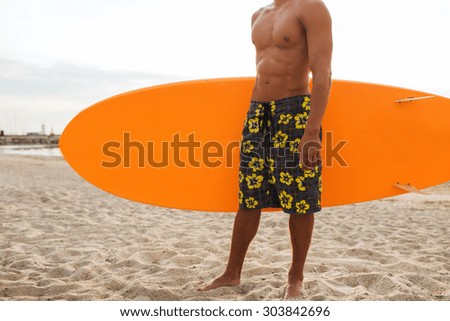sea, summer vacation, water sport and people concept - close up of young man with surfboard on beach
