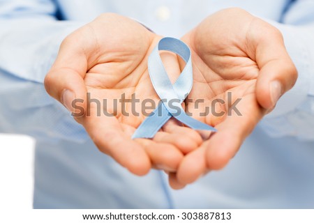 medicine, health care, gesture and people concept - close up of male hands holding blue prostate cancer awareness ribbon