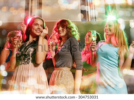 party, holidays, celebration, nightlife and people concept - smiling friends with glasses of champagne dancing in club
