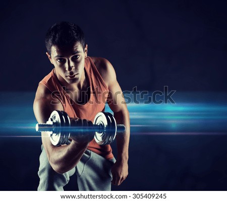 sport, bodybuilding, training and people concept - young man with dumbbell flexing biceps over dark background