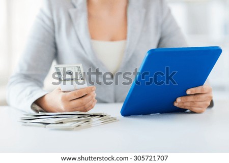 business, finance, saving, technology and people concept - close up of woman hands with tablet pc computer and us dollar money