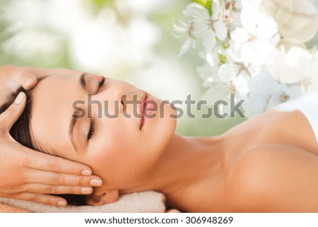 spa, beauty, people and body care concept - beautiful woman getting face treatment over green natural background