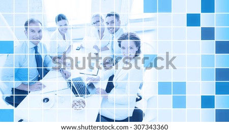 business, people and teamwork concept - business team with laptop computer and papers meeting in office over blue squared grid background