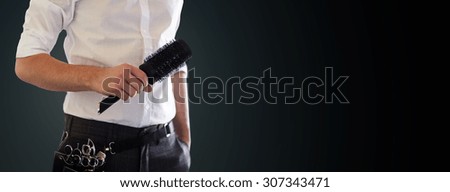 beauty and hair salon, hairstyle and people concept - close up of male stylist with brush at salon over blank black background