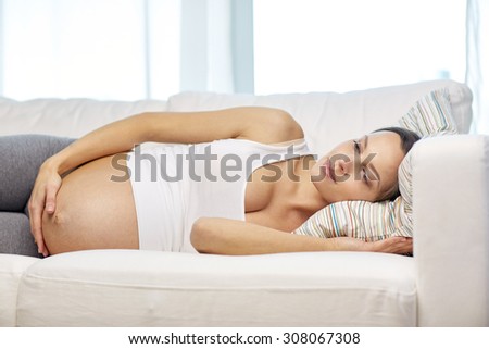 pregnancy, rest, people and expectation concept - happy pregnant woman lying on sofa at home