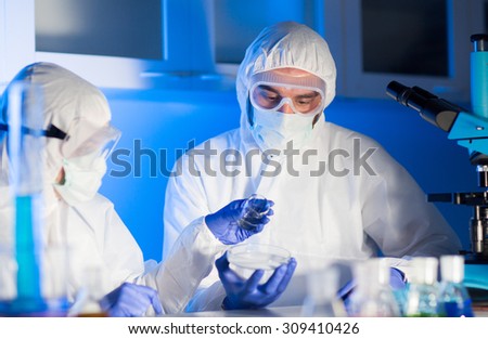 science, chemistry and people concept - close up of scientists with chemical samples in petri dish making test or research at laboratory
