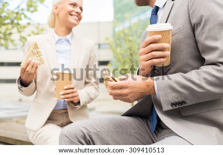 business, partnership, hot drinks and people concept - close up of smiling businessmen with coffee cups and sandwiches having lunch and talking outdoors