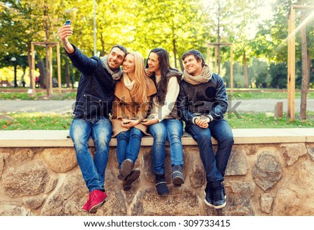 travel, vacation, people, technology and friendship concept - group of smiling friends making self portrait with smartphones in city park