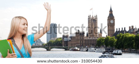 education, school, study abroad, gesture and people concept - smiling student with folders waving hand over london city and thames river background