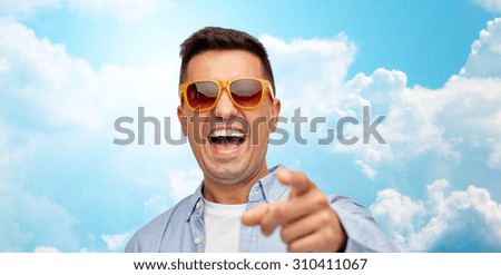 summer, style, emotions and people concept - face of laughing middle aged latin man in shirt and sunglasses over blue sky and clouds background