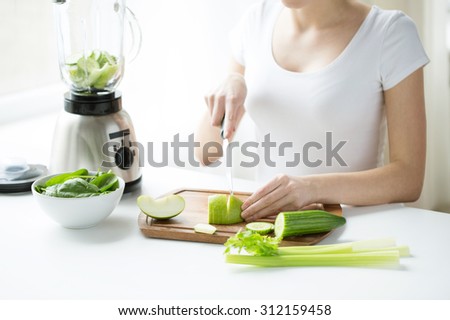 healthy eating, cooking, vegetarian food, dieting and people concept - close up of young woman with blender chopping green vegetables for detox shake or smoothie at home