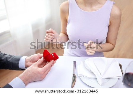 couple, love, engagement and holiday concept - close up of excited young woman and boyfriend giving her ring at restaurant