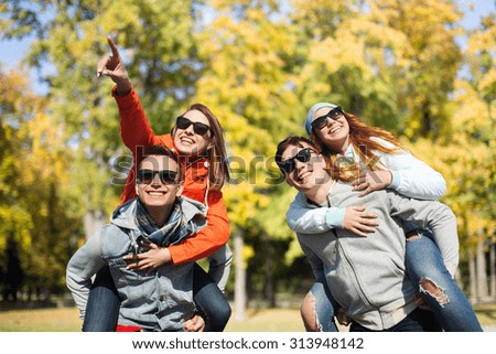 friendship, leisure, season and people concept - group of happy teenage friends in sunglasses having fun over autumn park background