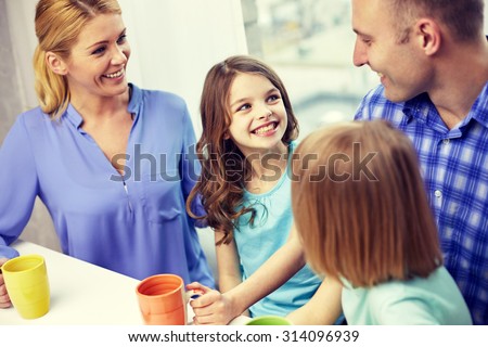 family, childhood, breakfast and people - happy parents and children drinking tea with cups at home