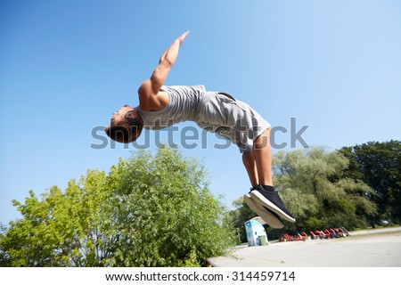 fitness, sport, parkour and people concept - young man jumping in summer park