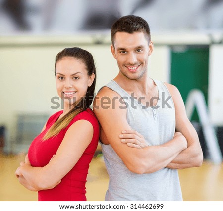 fitness, sport, training, gym and lifestyle concept - two smiling people in the gym