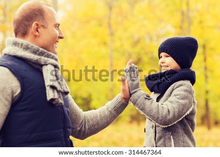 family, childhood, season, gesture and people concept - happy father and son making high five in autumn park