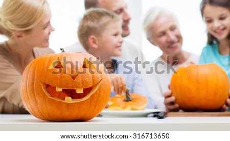 generation, holidays and people concept - helloween pumpkin lantern over happy family at home