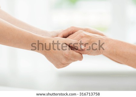 people, age, family, care and support concept - close up of senior woman and young woman holding hands