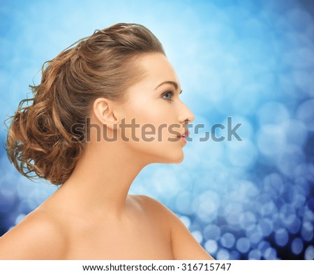 health, people and beauty concept - beautiful young woman face over blue holidays lights background
