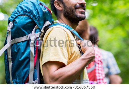 adventure, travel, tourism, hike and people concept - close up of friends walking with backpacks in woods