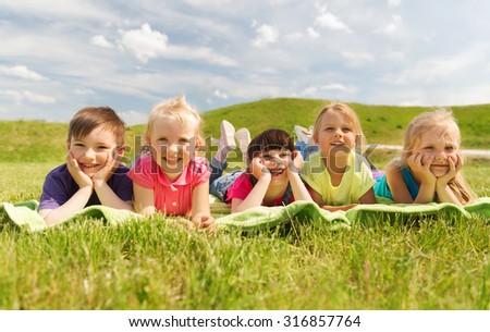 summer, childhood, leisure and people concept - group of happy kids lying on blanket or cover outdoors