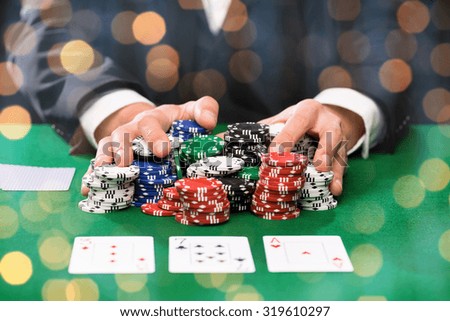 casino, gambling, poker, people and entertainment concept - close up of poker player with playing cards and chips at green casino table over holidays lights background