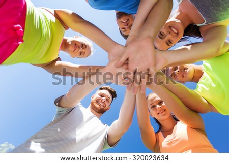 fitness, sport, friendship and healthy lifestyle concept - group of happy teenage friends with hands on top outdoors