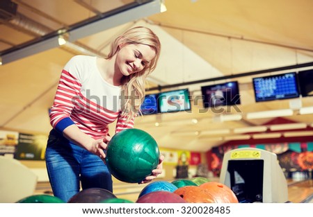 people, leisure, sport and entertainment concept - happy young woman holding ball in bowling club