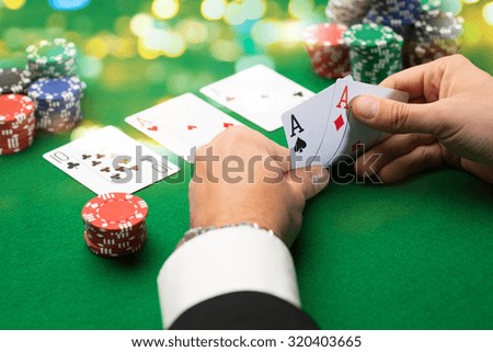 casino, gambling, poker, people and entertainment concept - close up of poker player with playing cards and chips at green casino table over holidays lights background