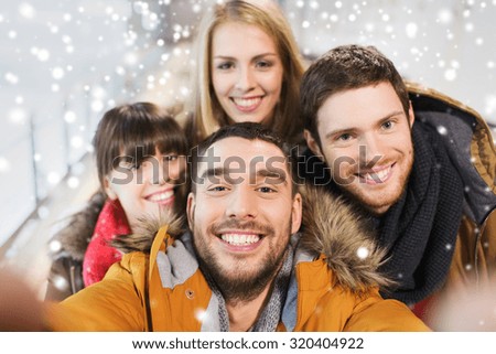 people, friendship, technology and leisure concept - happy friends taking selfie with camera or smartphone on skating rink
