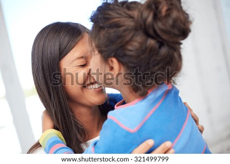 family, children, love and happy people concept - happy little girl hugging mother and kissing her on nose at home