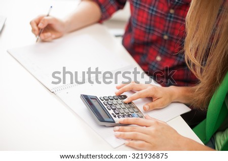 education, people, mathematics and high school concept - close up of students with notebook and calculator at school
