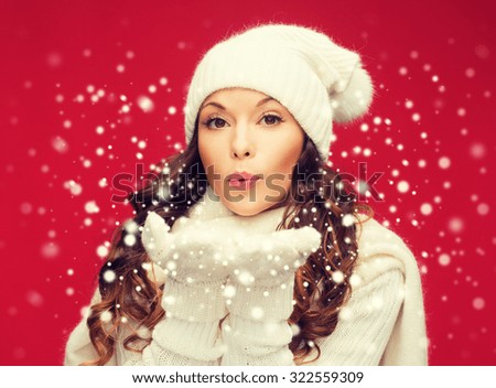 christmas, x-mas, people, happiness concept - happy woman in winter clothes blowing on palms