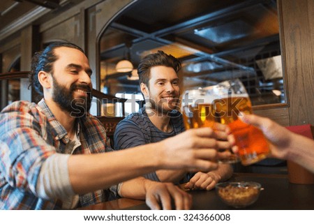 people, leisure, friendship, bachelor party and celebration concept - happy male friends drinking beer and clinking glasses at bar or pub