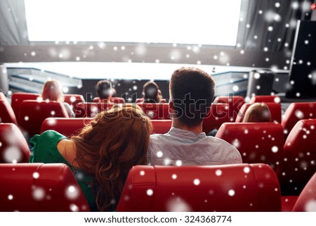 cinema, entertainment, leisure and people concept - happy couple watching movie in theater from back over snowflakes