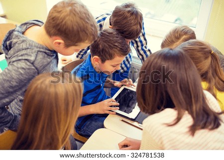 education, elementary school, learning, technology and people concept - group of school kids with tablet pc computer having fun on break in classroom