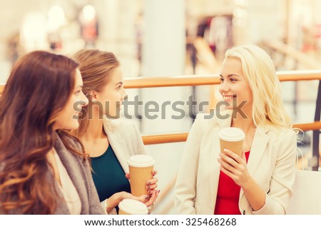 sale, consumerism and people concept - happy young women with shopping bags and coffee paper cups in mall