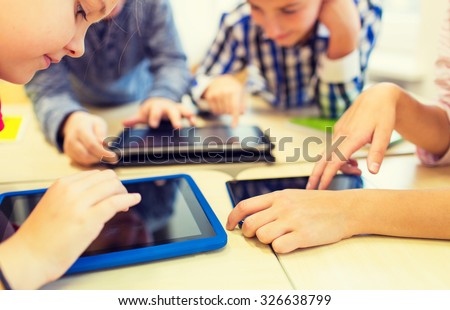 education, elementary school, learning, technology and people concept - close up of school kids with tablet pc computers having fun and playing on break in classroom