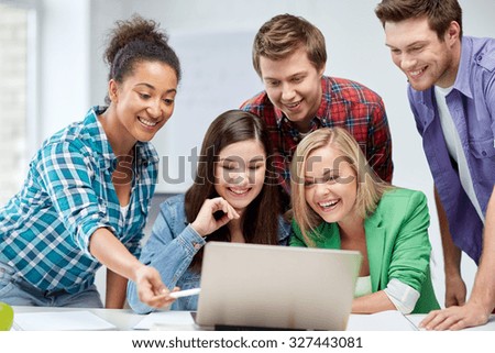 education, people, friendship, technology and learning concept - group of happy international high school students or classmates with laptop computer in classroom