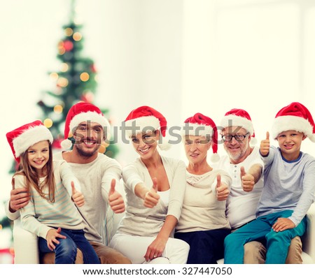 family, generation, gesture, holidays and people concept - happy family in santa helper hats showing thumbs up over living room and christmas tree lights background