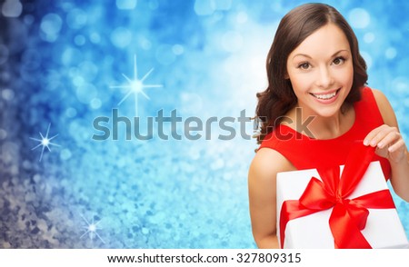 christmas, valentines day, birthday, people and holidays concept - smiling woman in red dress with gift box over blue glitter or lights background