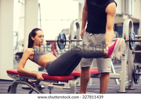 fitness, sport, training, teamwork and lifestyle concept - woman with personal trainer doing abdominal exercise in gym