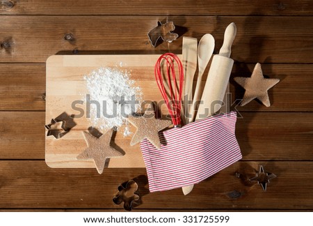 baking, cooking, christmas and food concept - close up of gingerbread cookies, molds with flour and kitchenware set on wooden cutting board at home kitchen from top