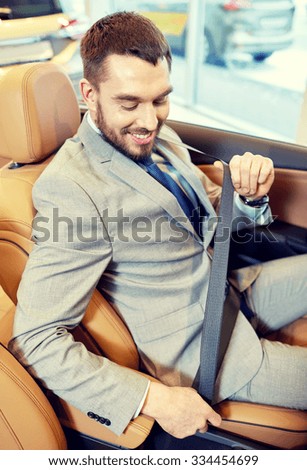 auto business, car sale, consumerism, technology and people concept - happy man sitting in car with smartphone at auto show or salon