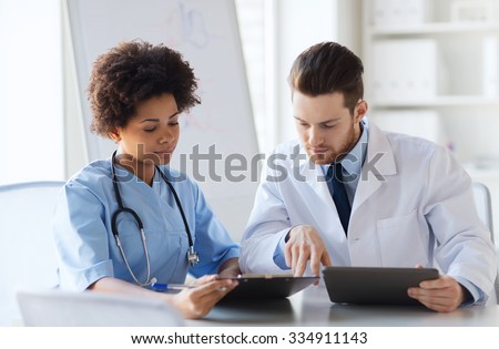hospital, profession, people and medicine concept - two doctors with tablet pc computer meeting and talking at medical office
