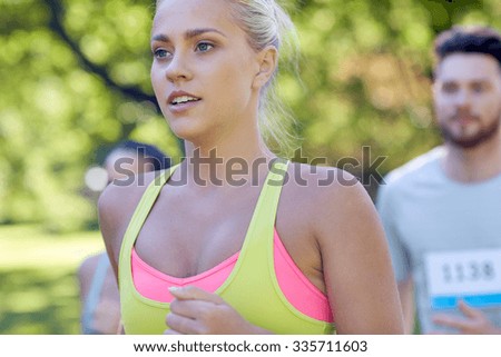 fitness, sport, friendship, race and healthy lifestyle concept - group of happy teenage friends or sportsmen running marathon with badge numbers outdoors