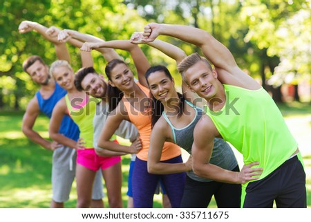 fitness, sport, friendship and healthy lifestyle concept - group of happy teenage friends or sportsmen exercising and stretching at boot camp