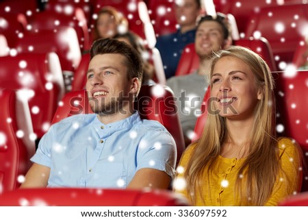 cinema, entertainment and people concept - happy friends or couple watching movie in theater over snowflakes