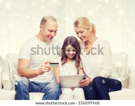 family, holidays, shopping, technology and people concept - happy family with tablet pc computer and credit card over snowflakes background